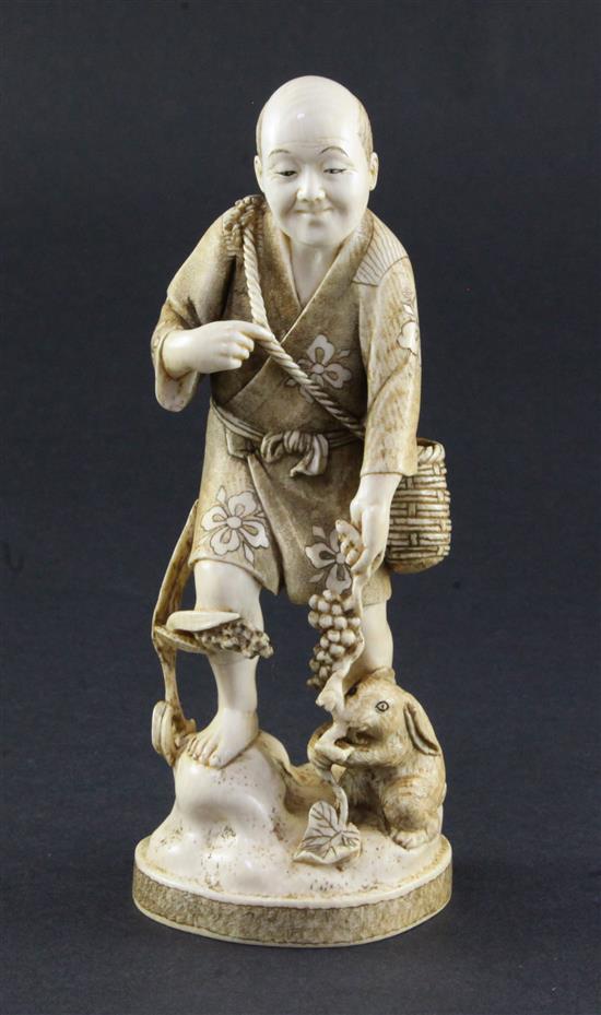 A Japanese ivory okimono of a farmer holding a vine, a rabbit at his feet, early 20th century, 16.5cm